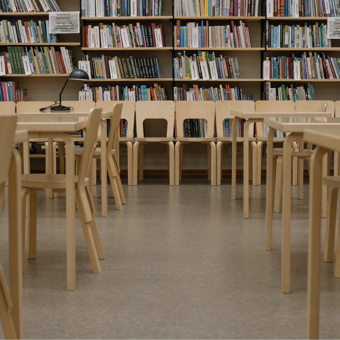 A room with tables and chairs and library books.